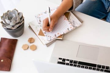 woman writing notes at a computer