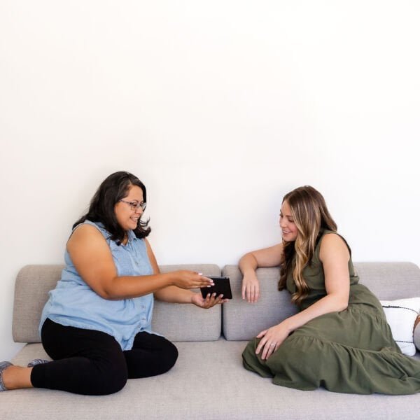 Two woman looking at an ebook on a sofa